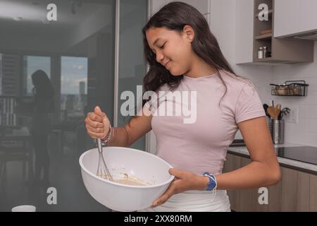 Teenager-Mädchen mischt die Zutaten mit einer Schüssel und einem Schneebesen. Stockfoto