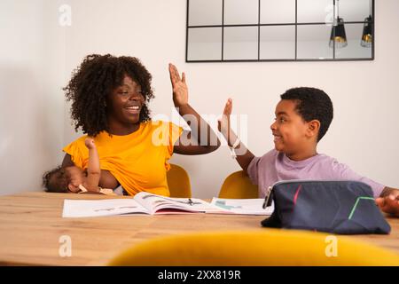 Glückliche Familie, die High-Five während der Hausaufgaben gibt Stockfoto