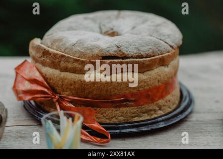 Rundes Partybrot mit rotem Band auf einem Holztisch Stockfoto