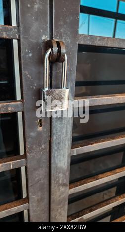 Langes Vorhängeschloss auf dem alten Grill. Ich schütze das Zuhause vor dem Eindringling. Stockfoto