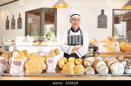 Bäckerei-Angestellter, der hinter Brot auf einem Regal in einer Bäckerei steht Stockfoto