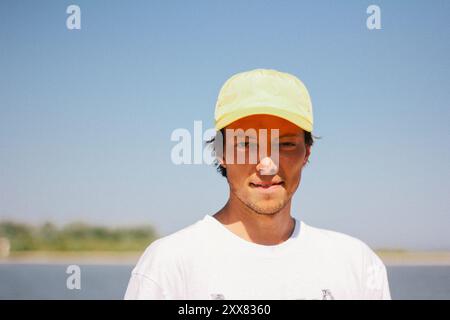 Ein junger Mann mit gelber Mütze genießt einen sonnigen Tag und lächelt. Stockfoto