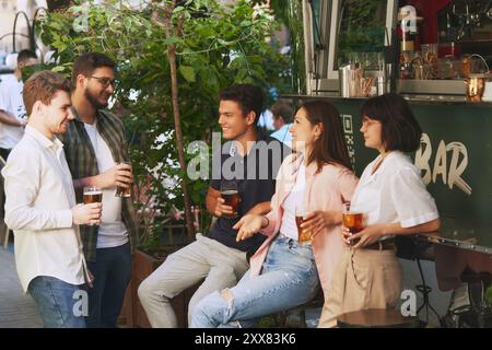 Freunde treffen sich im Freien, treffen sich an der trendigen Bar, genießen einen entspannten Nachmittag in guter Gesellschaft, trinken Bier und haben eine gute Zeit zum Entspannen. Stockfoto