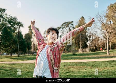 Junger asiatischer Mann, der Freiheit auf dem Land genießt junger Mann, der Arme spreizt und frische Luft mit geschlossenen Augen atmet, während er auf trockenem Feld steht Stockfoto