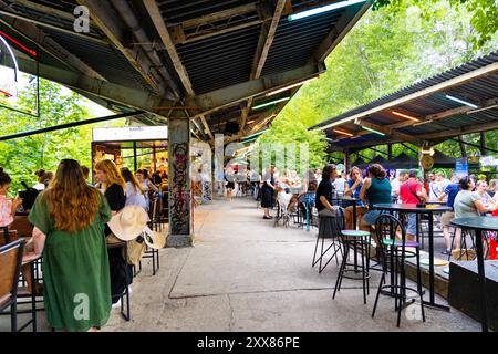 Menschen essen auf dem Open-Air-Markt Nocny Market (Nachtmarkt) auf den ehemaligen Bahnsteigen des Hauptbahnhofs in Warschau, Polen Stockfoto