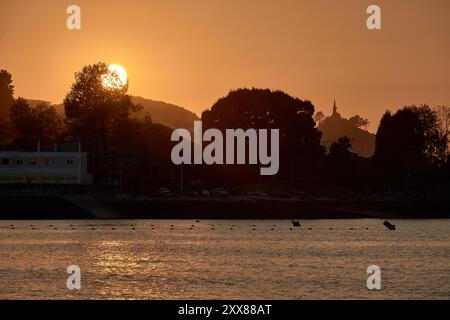 Einzigartiger Sonnenuntergang am Ladeira Beach, wo die Sonne hinter einem einsamen Baum untergeht und eine markante Silhouette am Abendhimmel schafft Stockfoto