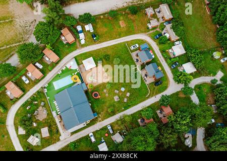 Blick von oben auf den Campingplatz mit Hütten, Bungalows, Wohnwagen, Swimmingpool, Spielplatz, von oben nach unten. Sommerferien Camping Hintergrundkonzept. Stockfoto