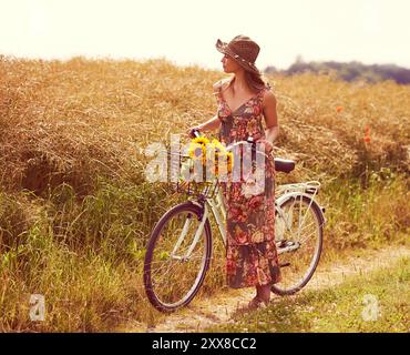 Sonnenblumen, auf dem Land oder eine Frau auf dem Fahrrad im Feld, die an Urlaub, Abenteuer oder Wellness denkt, um in der Natur zu entspannen. Bauernhof, Ausflug oder Mädchen auf dem Fahrrad für Öko Stockfoto