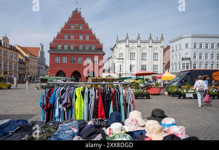 Greifswald, Deutschland. August 2024. Blick über den Markt mit dem Wochenmarkt zum Rathaus (l). Unter dem Motto „Street Art in Friedrichs Zeit“ feiert Greifswald in diesem Jubiläumsjahr an zwei Tagen das Stadtfest zu Ehren von Caspar David Friedrich. Das Festival findet auf dem Marktplatz und an anderen Orten im Stadtzentrum statt. Quelle: Stefan sauer/dpa/Alamy Live News Stockfoto