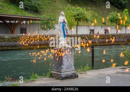 Frankreich, Hautes Pyrenäen, Lourdes, der Schrein Notre Dame de Lourdes, die Marienstatue vor den Brennern und die Reflexion der Kerzenflammen Stockfoto