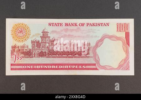 Rot-orange alte pakistanische 100-Rupie-Banknote mit Islamia-Kolleg in Peschawar-Porträt (nicht mehr im Umlauf). Stockfoto