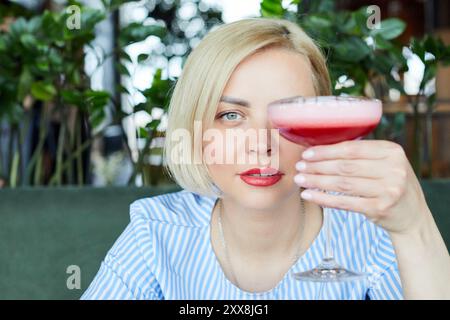 Porträt einer attraktiven jungen Frau, die im Café drinnen Koktopf trinkt Stockfoto