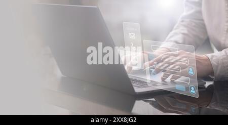 Ein Geschäftsmann arbeitet an seinem Laptop, mit einem Hologramm eines Chatbots, das vor ihm leuchtet. Er nutzt KI-Technologie, um seine zu verwalten und zu verbessern Stockfoto