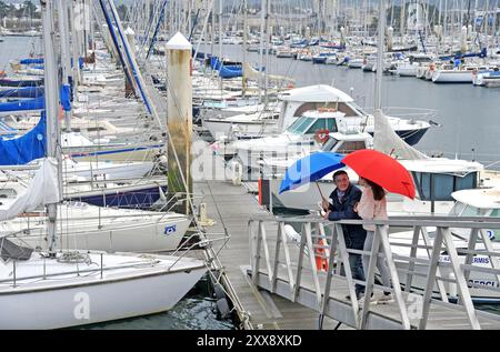 Frankreich, Manche, Cherbourg-en-Cotentin, Cherbourg Regenschirmfabrik, Herstellung von Luxusschirmen, Ein Paar mit Regenschirmen am Yachthafen Stockfoto