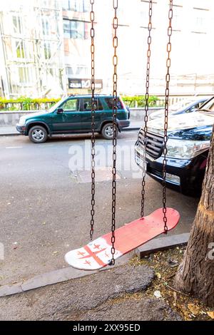 Tiflis, Georgien - 14. August 2024: Altes Skateboard mit georgischer Flagge in einer Straße in Tiflis, Georgien, zu einer Schlinge gemacht. Stockfoto