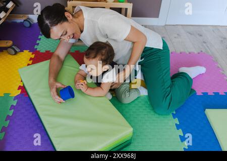 Kleiner Junge mit muskuloskelettalen Erkrankungen im Reha-Korsett nimmt mit Hilfe eines Therapeuten im Therapieraum eine körperliche Rehabilitation ein Stockfoto