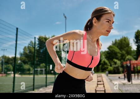 Eine junge Frau mit Vitiligo, die ein rosafarbenes Oberteil trägt, trainiert in einem Park im Freien. Stockfoto