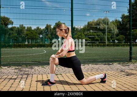 Eine junge Frau mit Vitiligo zieht sich an einem sonnigen Tag im Park, trägt ein rosafarbenes Oberteil und schwarze Shorts. Stockfoto