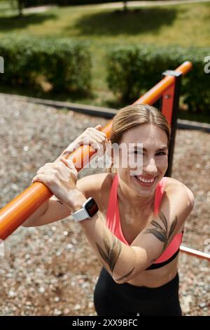 Eine junge Frau mit Vitiligo, die ein rosafarbenes Oberteil trägt, lächelt, während sie in einer horizontalen Bar im Park arbeitet. Stockfoto