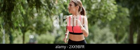 Eine junge Frau mit Vitiligo läuft durch einen Park, trägt einen pinken Sport-BH und schwarze Leggings. Stockfoto