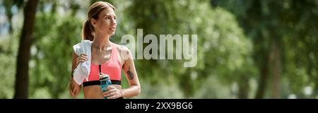 Eine junge Frau mit Vitiligo, die ein rosafarbenes Oberteil und aktive Kleidung trägt, macht eine Pause von ihrem Workout in einem Park. Stockfoto