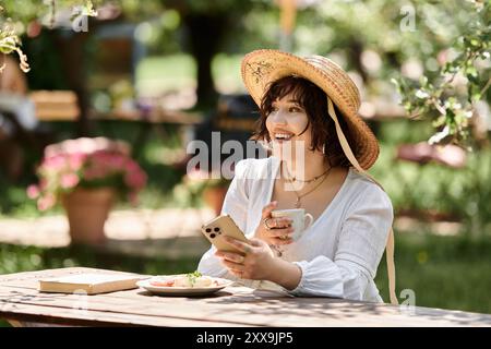 Eine brünette Frau in einem weißen Kleid genießt einen Sommerbrunch im Freien, umgeben von Natur und Sonne. Stockfoto