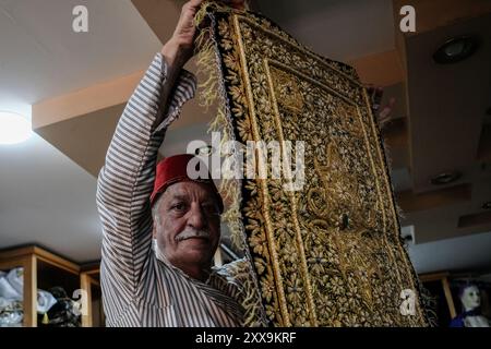 Der Jerusalemer Textilhändler Bilal Abu Khalaf steht in seinem Geschäft im Christlichen Viertel der Altstadt, umgeben von Textilien, die die seiner Familie zeigen Stockfoto