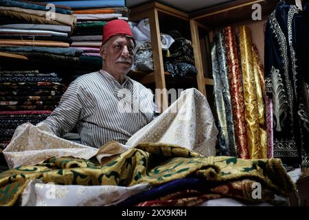 Der Jerusalemer Textilhändler Bilal Abu Khalaf steht in seinem Geschäft im Christlichen Viertel der Altstadt, umgeben von Textilien, die die seiner Familie zeigen Stockfoto