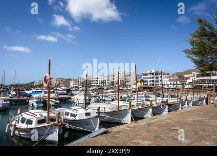 Port de Pollenca, Mallorca, Spanien - 24. April 2024: Kleine Fischerboote im Hafen und eine Strandpromenade. Stockfoto