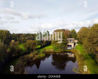 Fernansicht der hinteren Höhe von der anderen Seite des Teichs. Serenity - Scawby Brook, Scawby Brook, Großbritannien. Architekt: Kelly und Macpherson Arc Stockfoto