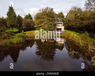 Fernsicht von der anderen Seite des Teichs, die hintere Südhöhe des Hauses. Serenity - Scawby Brook, Scawby Brook, Großbritannien. Architekt: Stockfoto