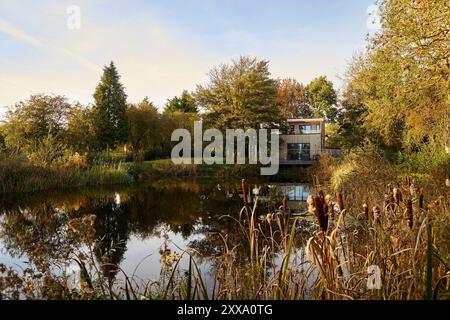 Fernsicht von der anderen Seite des Teichs auf die hintere Südhöhe des Hauses. Serenity - Scawby Brook, Scawby Brook, Großbritannien. Architec Stockfoto