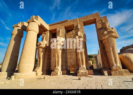 Blick auf die Ramesssstatuen am Eingang zum Ramesseum, dem Leichentempel von Pharoah Ramesses II. Dem Großen an einem hellen Nachmittag mit blauem Himmel in Luxor, Ägypten Stockfoto