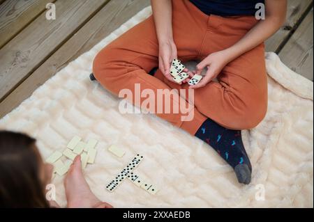 Zwei Personen, die in einem Domino-Spiel auf einer weichen Decke mit Schwerpunkt auf Freizeit und Strategie in Innenräumen spielen. Stockfoto