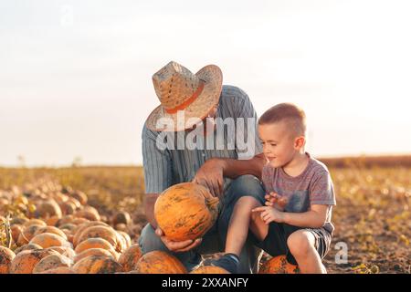 Senior Farmer mit seinem Enkel auf dem Kürbisfeld. Stockfoto