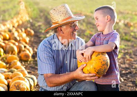 Senior Farmer mit seinem Enkel auf dem Kürbisfeld. Stockfoto