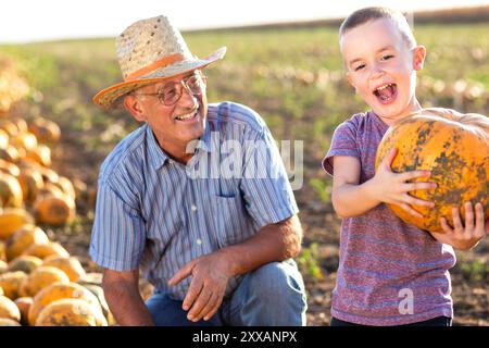 Senior Farmer mit seinem Enkel auf dem Kürbisfeld. Stockfoto