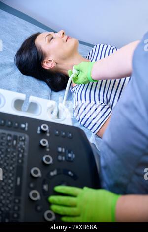 Der Arzt führt eine Ultraschalluntersuchung der Lymphknoten von Patienten mittleren Alters durch Stockfoto