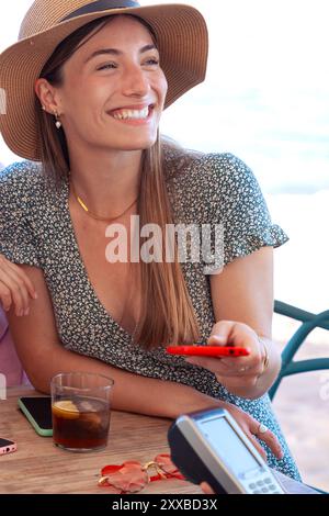 Junge Frauen zahlen kontaktlos über die Handy-App im Restaurant Stockfoto