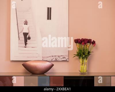 Gefälschte Tulpen in lila Tönen für die Zimmerdekoration, die neben einem Gemälde und einem lila Einrichtungsgegenstand platziert wurde Stockfoto