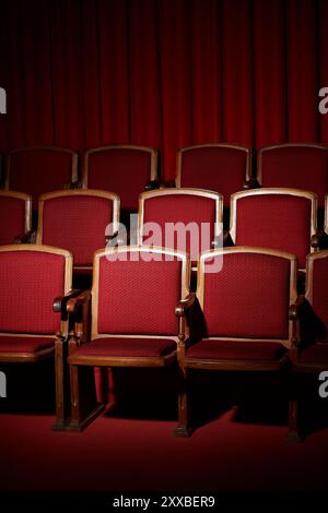 Leere rote Theatersitze unter einem roten Vorhang. Stockfoto