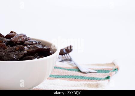 Schüssel mit getrockneten Datteln auf der linken Seite des Bildes und Gabel mit unscharfem Datum auf der rechten Seite der Schüssel. Stockfoto