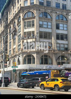 Männer arbeiten über der Straße an Gebäuden am Broadway und Houston am nördlichen Rand des SOHO-Viertels in Manhattan, New York City. Stockfoto