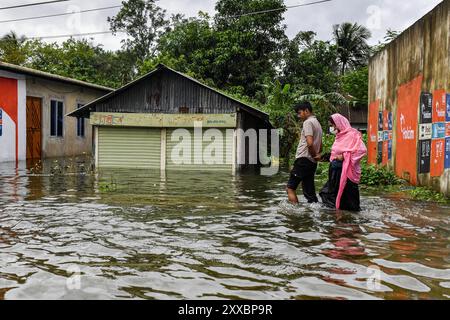 Dhaka, Dhaka, Bangladesch. August 2024. Menschen waten am 23. August 2024 durch Hochwasser im Mohipal, Bezirk Feni in der Division Chittagong, Bangladesch. Mindestens 13 Menschen werden getötet, insgesamt 43 Uupazilas in mehreren Bezirken sind von den Sturzfluten betroffen, und etwa 189.663 Familien werden gedrängt. (Kreditbild: © Zabed Hasnain Chowdhury/ZUMA Press Wire) NUR REDAKTIONELLE VERWENDUNG! Nicht für kommerzielle ZWECKE! Stockfoto