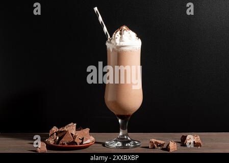 Schokoladen-Smoothie oder Milchshake und Schokoladenstücke auf schwarzem Holzhintergrund, Kopierraum. Gesundes Frühstücksprotein reichhaltiges Schokoladengetränk mit Peitsche Stockfoto