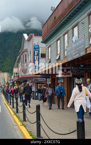 Touristen drängen den Bürgersteig entlang der South Franklin St. in der Nähe der Kreuzfahrtschiffpiers in Alaskas Hauptstadt unter niedrigen Wolken. Stockfoto