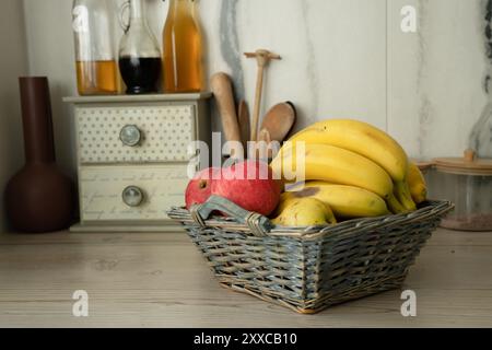 Korb mit frischem Obst auf dem Tisch in der Küche, Bananen auf dem Vorplatz Stockfoto