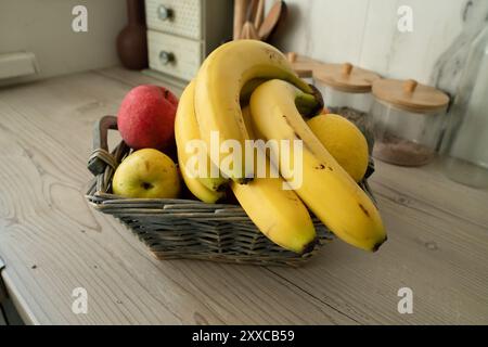 Korb mit frischem Obst auf dem Tisch in der Küche, Bananen auf dem Vorplatz Stockfoto