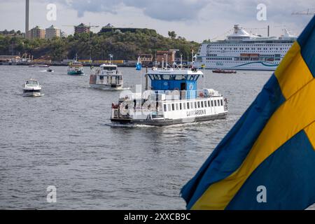 Eine geschäftige Hafenszene mit verschiedenen Booten und Fähren, die auf dem Wasser navigieren. Im Vordergrund steht eine Fähre mit dem Namen „Djurgården 8“ Stockfoto