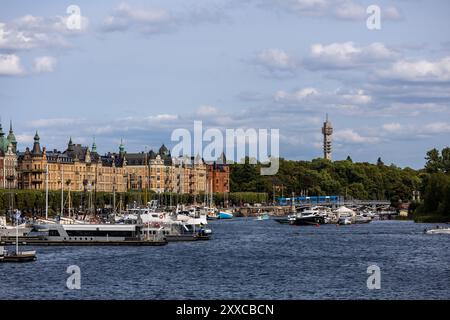 Ein malerischer Blick auf eine Uferpromenade in einer Stadt mit Booten, die entlang des Flusses angedockt sind. Historische Gebäude mit kunstvoller Architektur säumen das Ufer und ein Tal Stockfoto